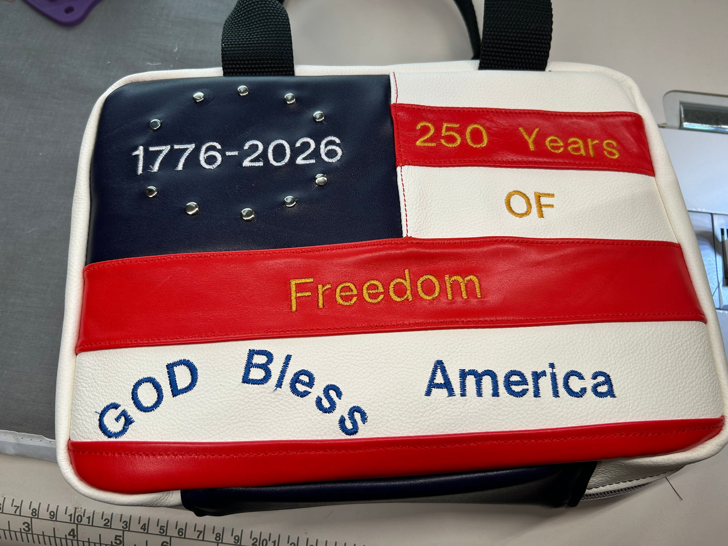 Bag with American flag design and text celebrating 250 years of freedom and America, with a ruler for scale.